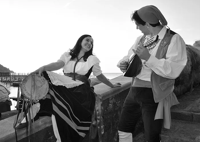 Black-and-white photo of a serenade: the dancer plays the mandolino for his partner on the wall