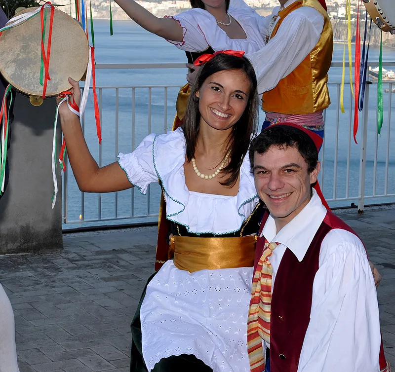 Close-up of a smiling couple in costume among tambourines decorated with colourful ribbons