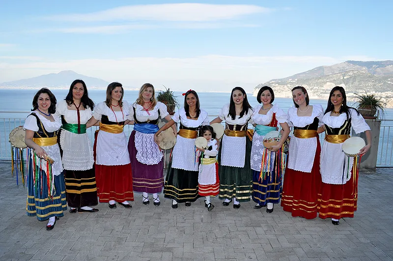 The Sorrento Folk female dancers lined up with tambourines on a terrace above the bay