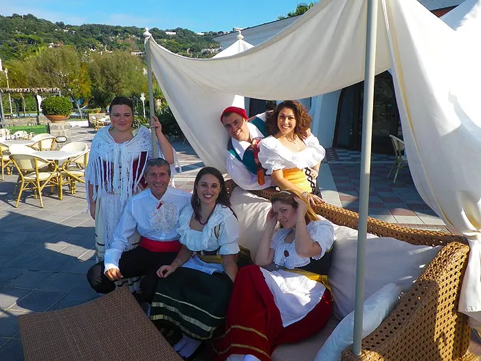 Dancers in costume taking a break on a sofa under a gazebo at a beach club