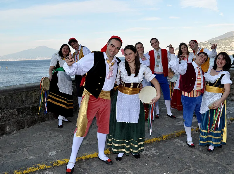The costumed group, cheerful and smiling, on the seafront with Vesuvius in the background