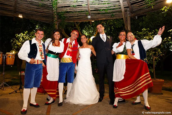 Sposi con i ballerini di tarantella sotto un pergolato