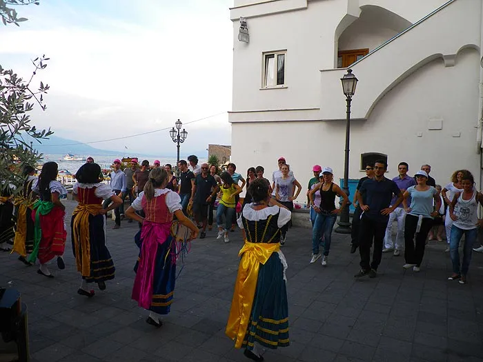Dancers in costume dancing in the square among tourists during an outdoor event