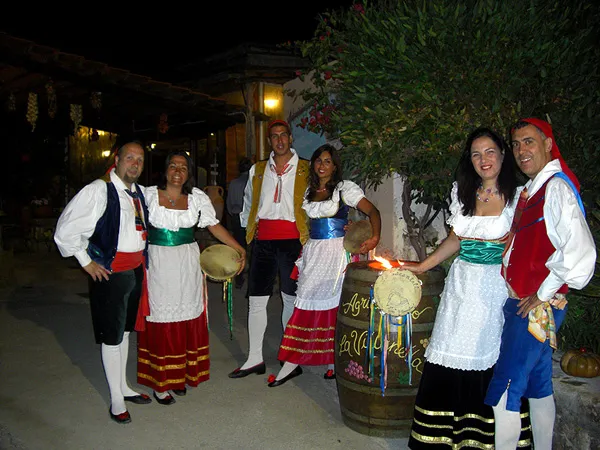 Couples in costume beside a wine barrel during an open-air evening at a restaurant
