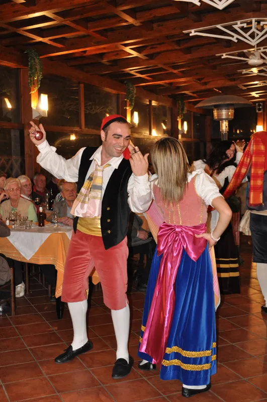 A couple dancing the tarantella in a beamed restaurant room among the diners