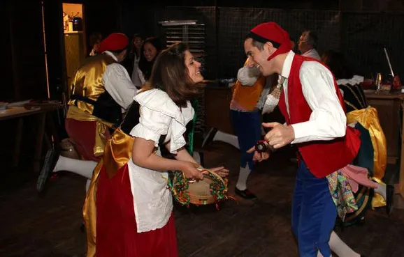 A couple dancing the tarantella sorrentina with a tambourine in a restaurant at night