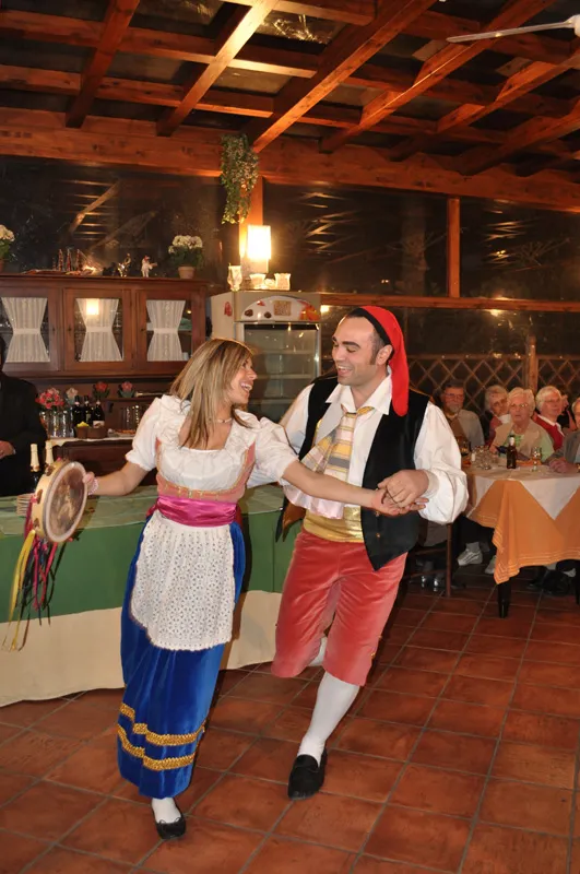 A couple dancing with a tambourine on a restaurant veranda in front of the guests