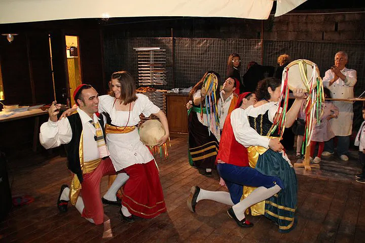 Couples dance the tarantella sorrentina with tambourines on a restaurant’s wooden floor