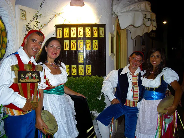 Two couples in costume posing at the entrance of a tavern during an evening show