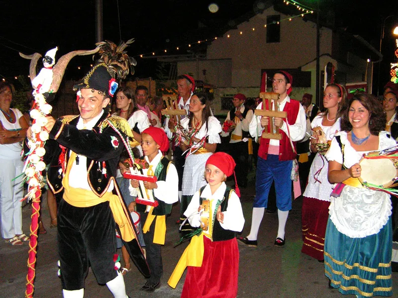 A night-time street parade led by the Pazzariello, with dancers and children in costume