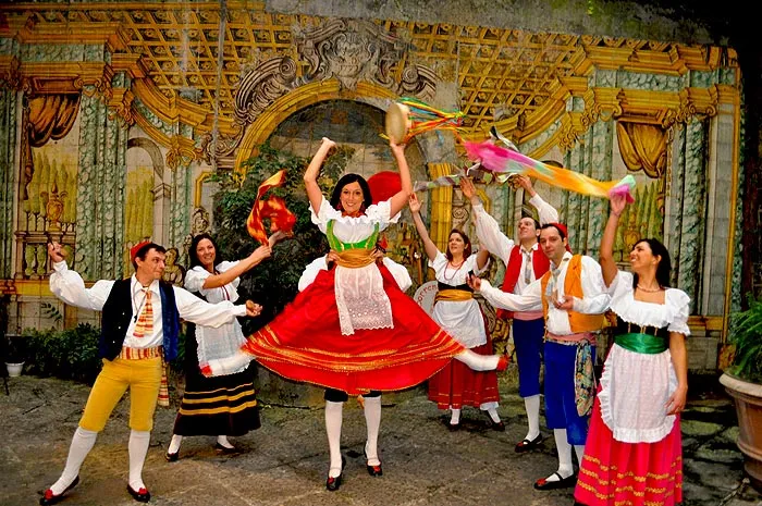 Una ballerina con la gonna rossa volteggia al centro del gruppo durante la tarantella sorrentina