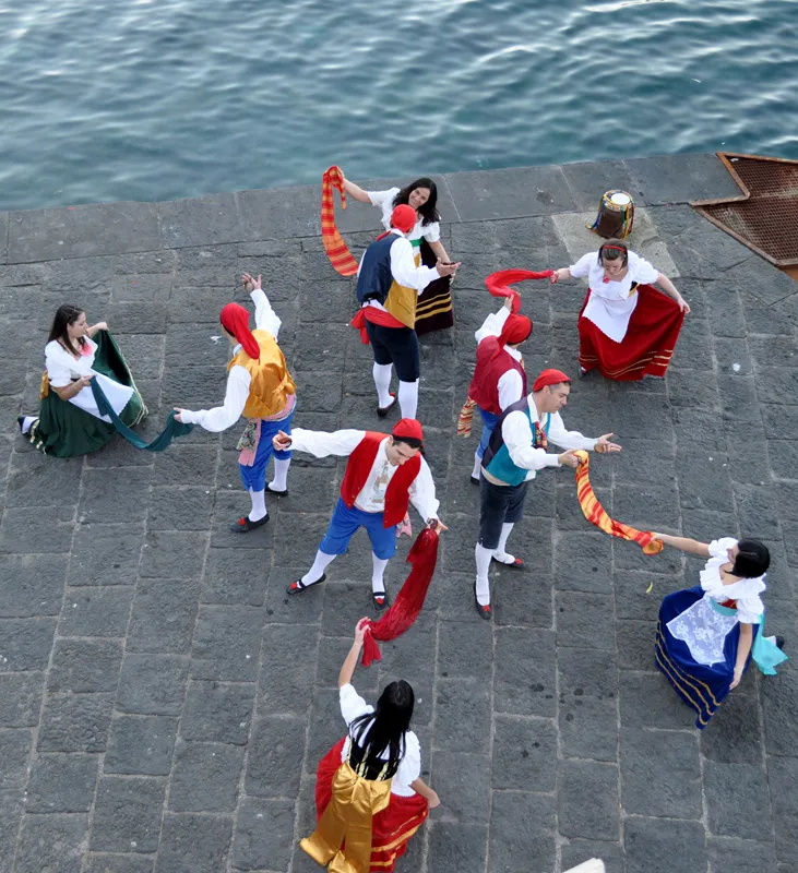 Vista dall’alto della danza dei foulard rossi su un molo in pietra a picco sul mare
