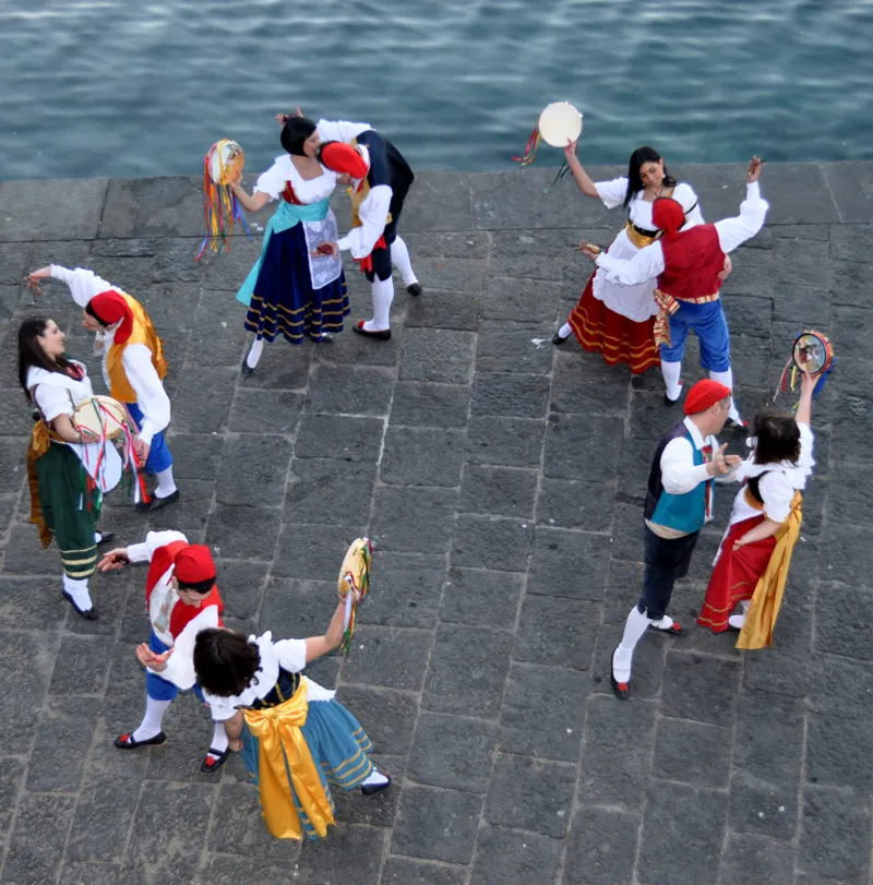 Vista dall’alto delle coppie che danzano la tarantella sorrentina su un molo in pietra lavica sul mare