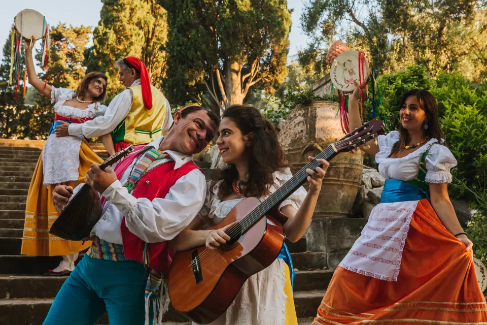 Ballerini di tarantella sorrentina con tamburelli e chitarra su una scalinata in giardino